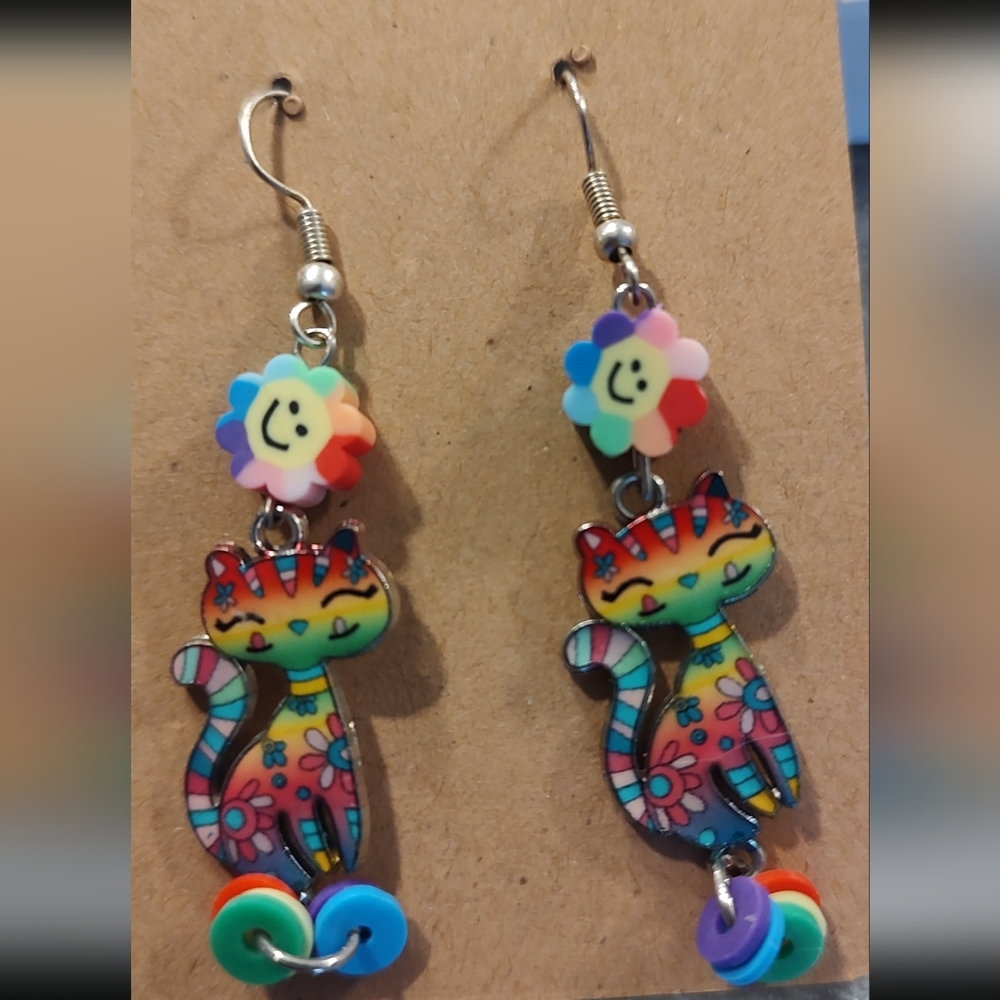 Rainbow cat earrings with smiley flower accents.
